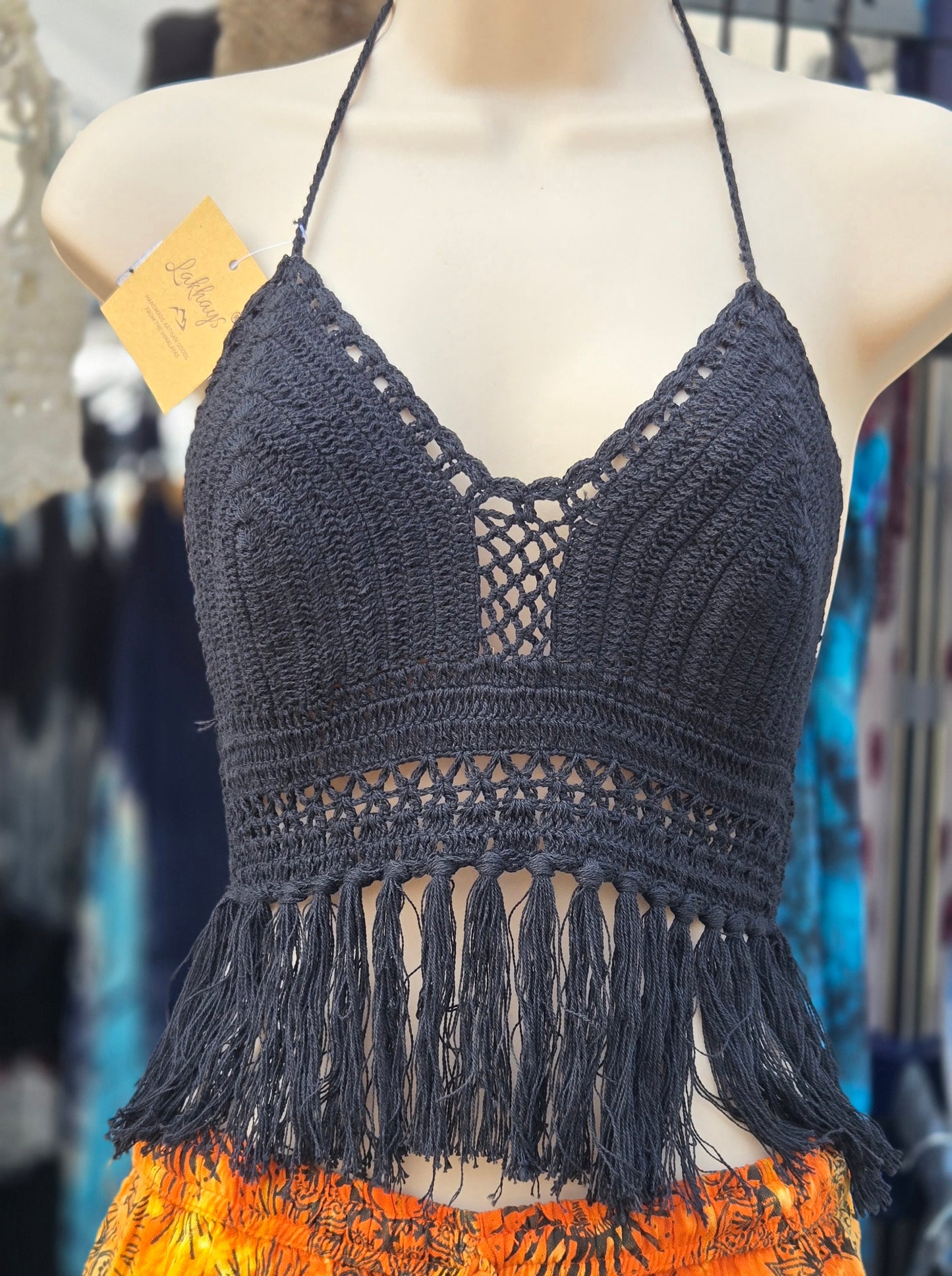 Black crochet halter top with fringe on a mannequin in a store setting