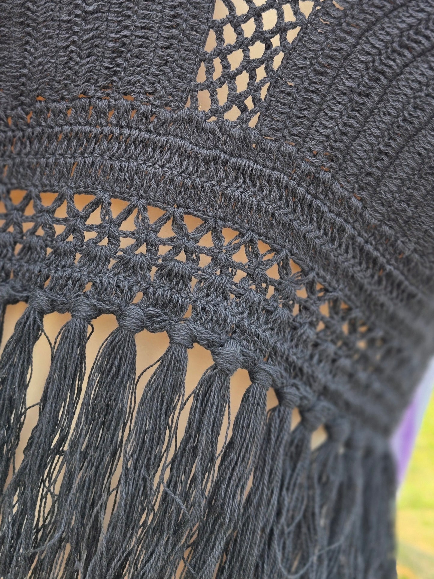 Close-up of a black crochet halter top with fringe details.