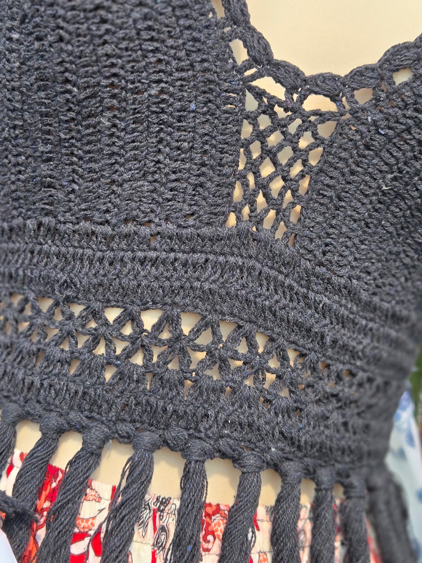 Close-up of a black crochet halter top with intricate patterns and fringe