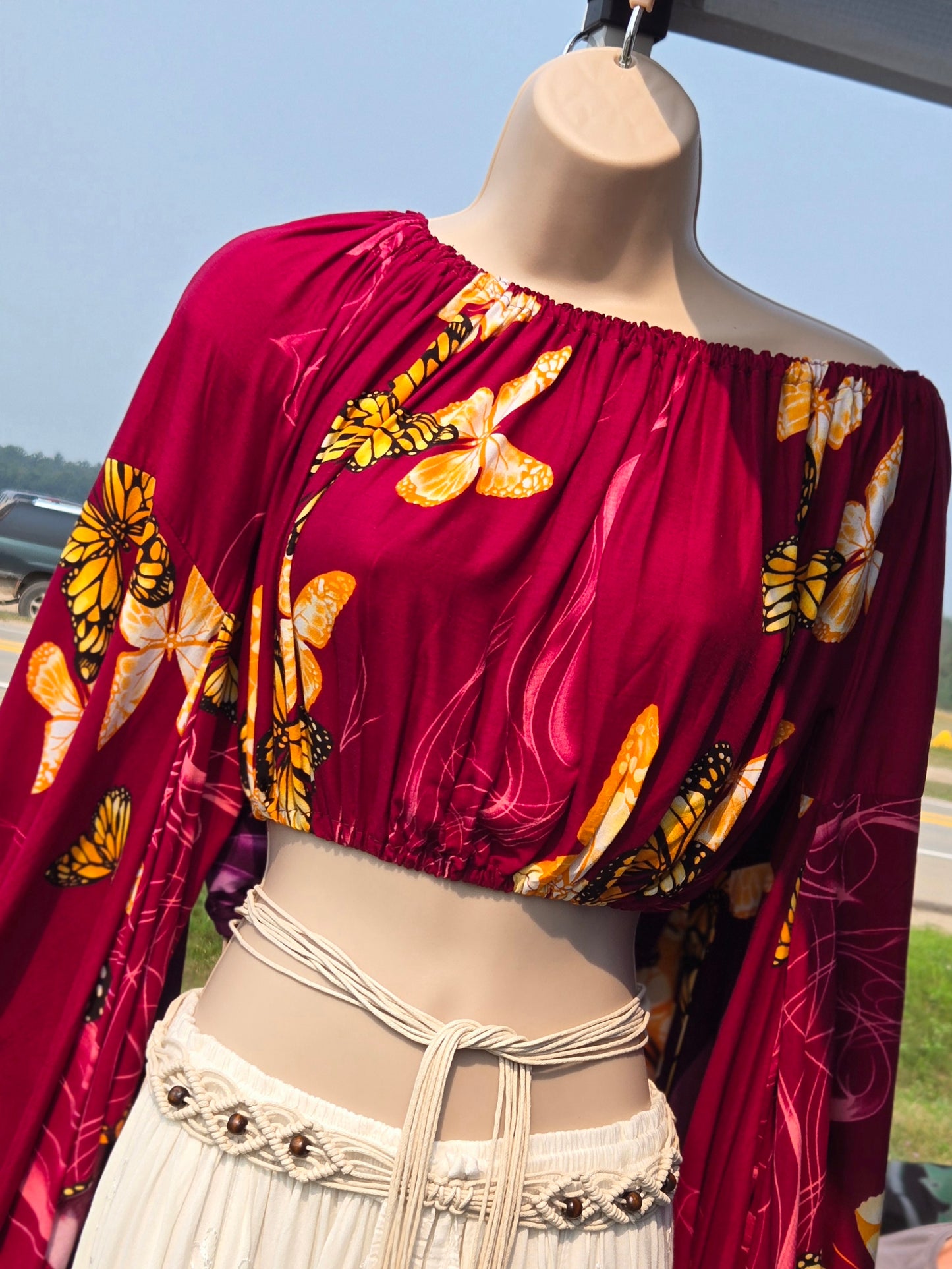 Mannequin wearing a red crop top with butterfly pattern outdoors