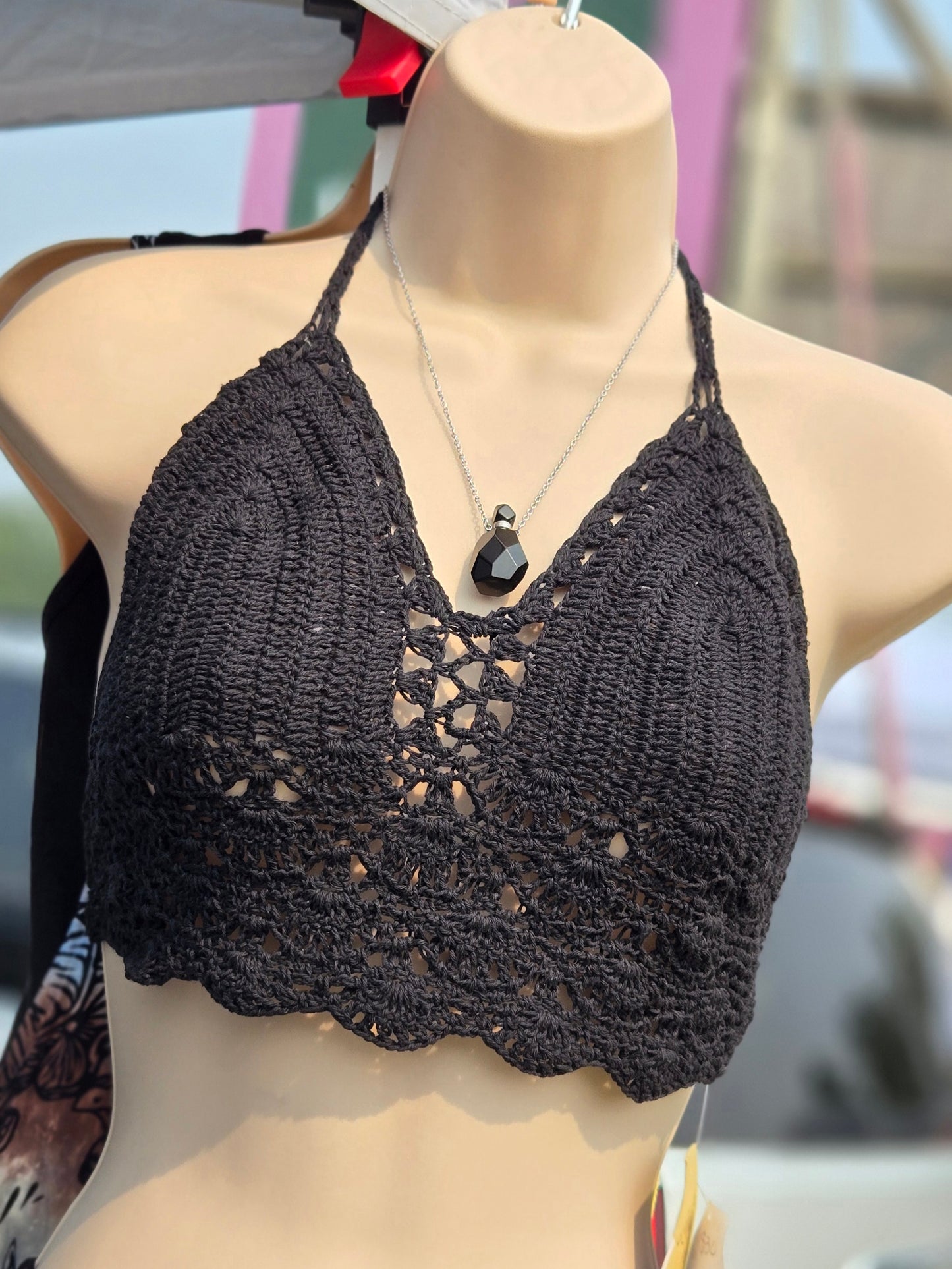 Black crochet halter top on a mannequin with a blurred background