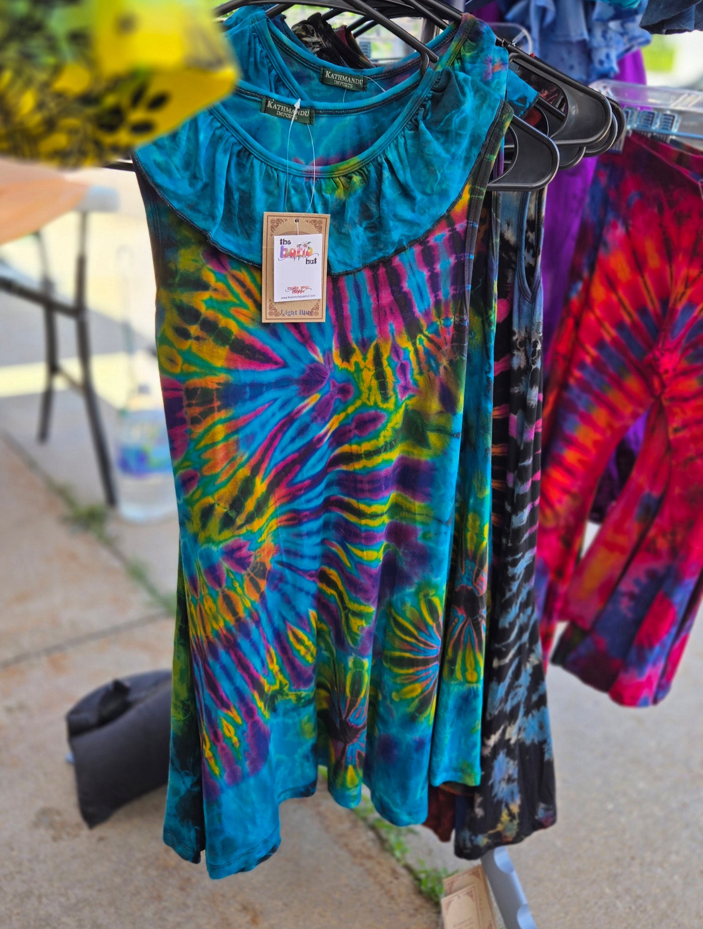 Colorful girls tie-dye dresses hanging on a rack outdoors