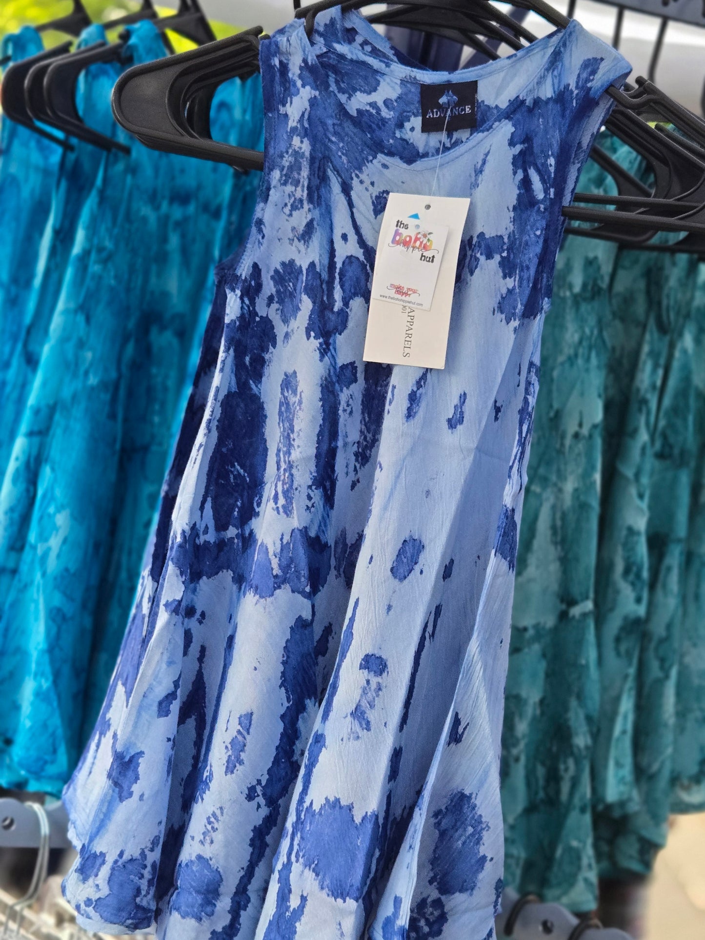 Blue girls tie dye dress on a rack with a tag, surrounded by other dresses.