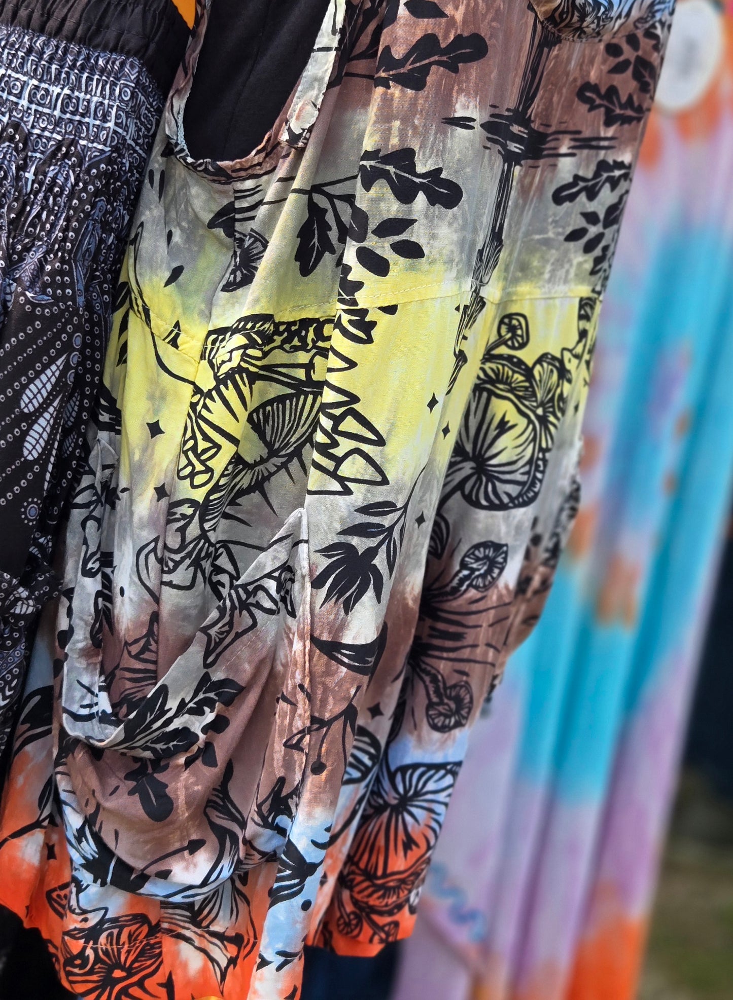 Close-up of colorful shortalls with mushroom patterns in black, orange, and yellow.