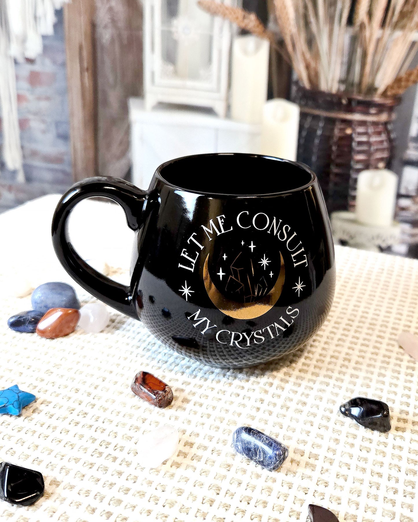 black coffee mug that says let me consult my crystals with moon and crystal design in gold