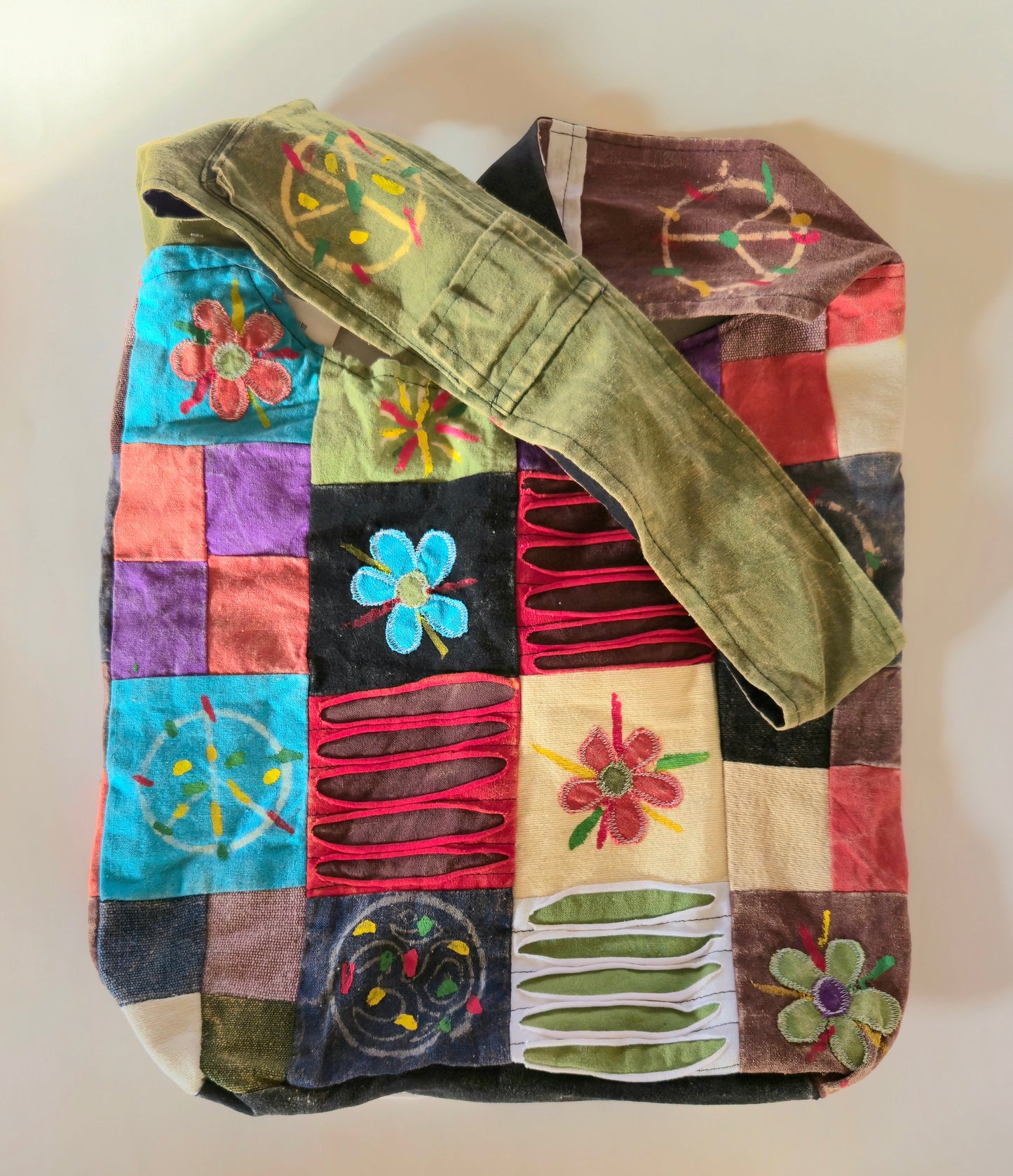 A multicolored hobo bag with a patchwork design, featuring a shoulder strap and a variety of vibrant patterns.