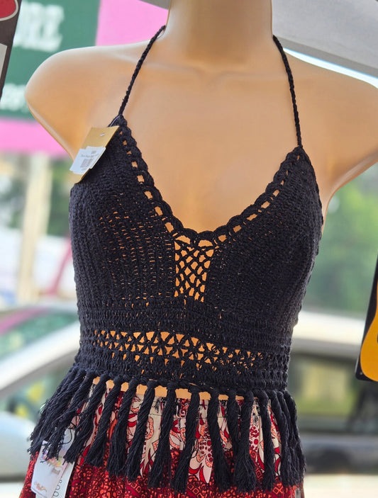 Black crochet top with fringe on a mannequin against a blurred outdoor background