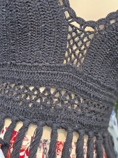 Close-up of a black crochet halter top with intricate patterns and fringe