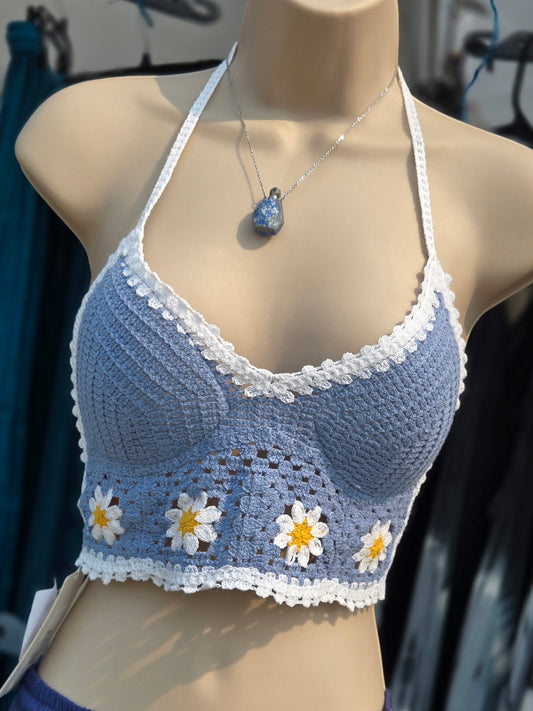 Blue crochet top with white border and daisy patterns on a mannequin.