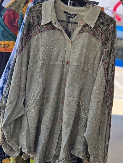 Green embroidered blouse on a hanger with colorful fabric in the background