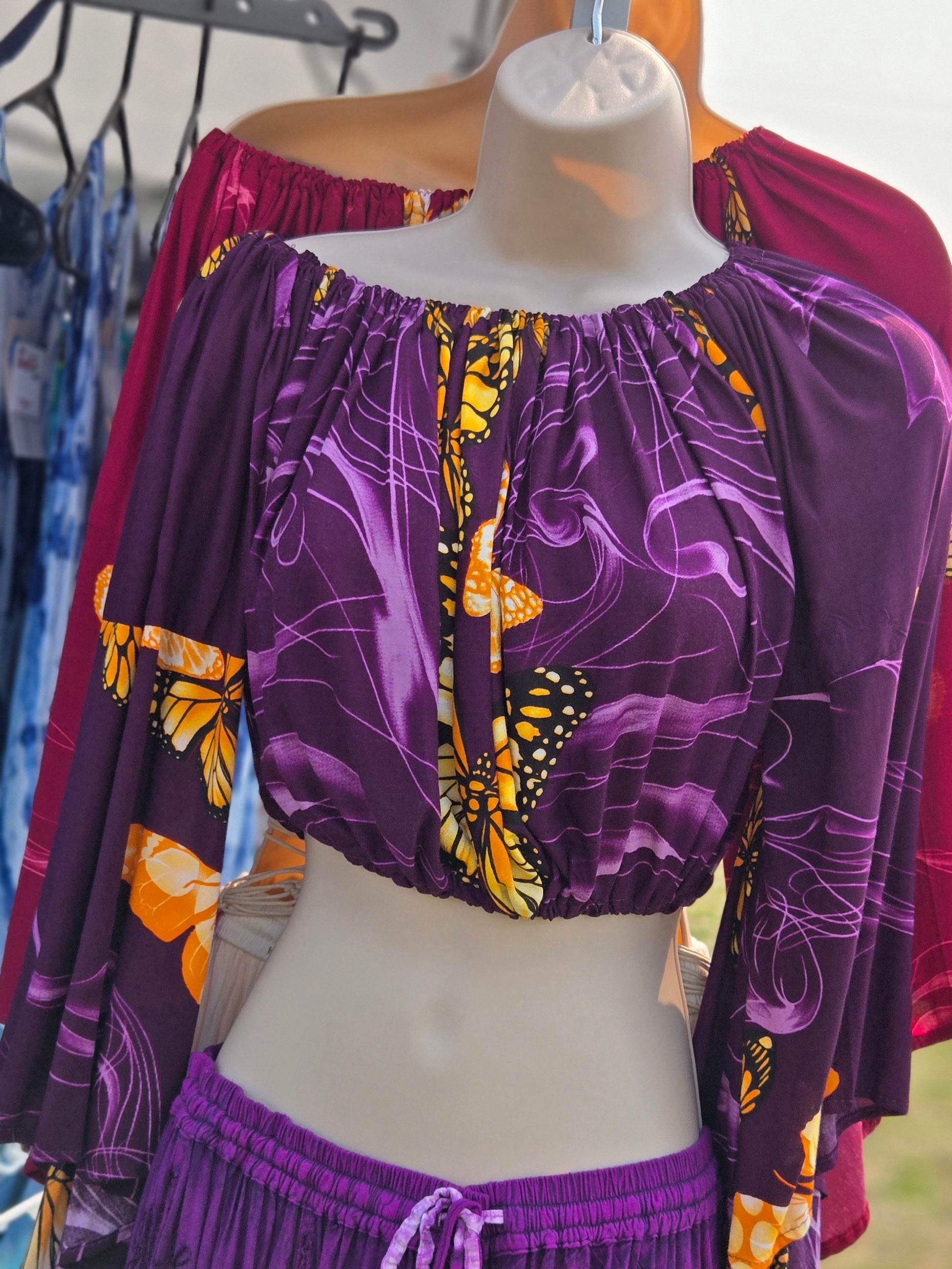 Purple butterfly patterned crop top and skirt set on a mannequin with blurred background