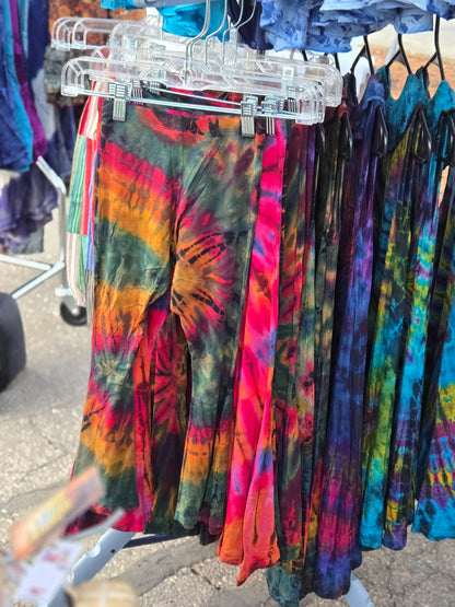 Colorful kids tie-dye bell bottom pants hanging on a rack outdoors.