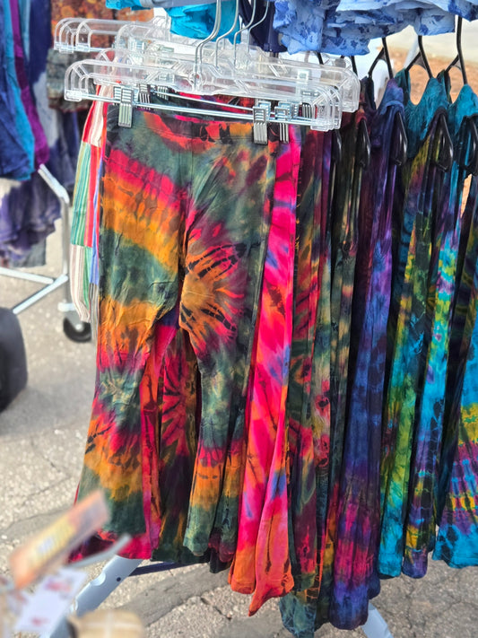 Colorful kids tie-dye bell bottom pants hanging on a rack outdoors.