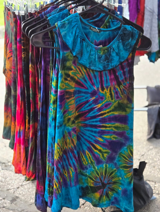Colorful girls tie-dye dresses hanging on a rack outdoors.