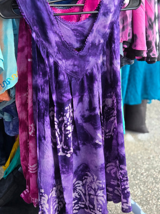Purple tie dye tank top hanging on a rack with other clothes in the background.