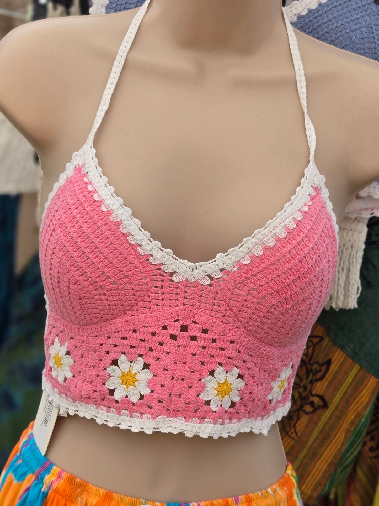 Pink crochet halter top with white daisy patterns on a mannequin