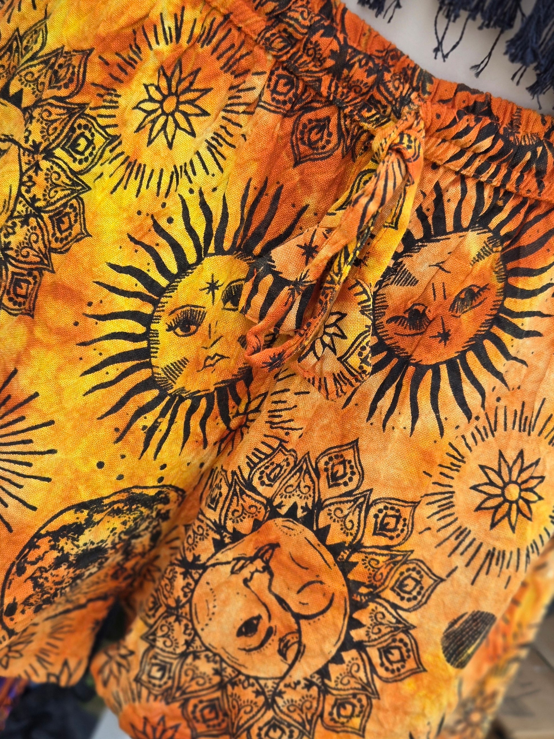 Close up of shorts with sun and moon designs on a yellow and orange fabric