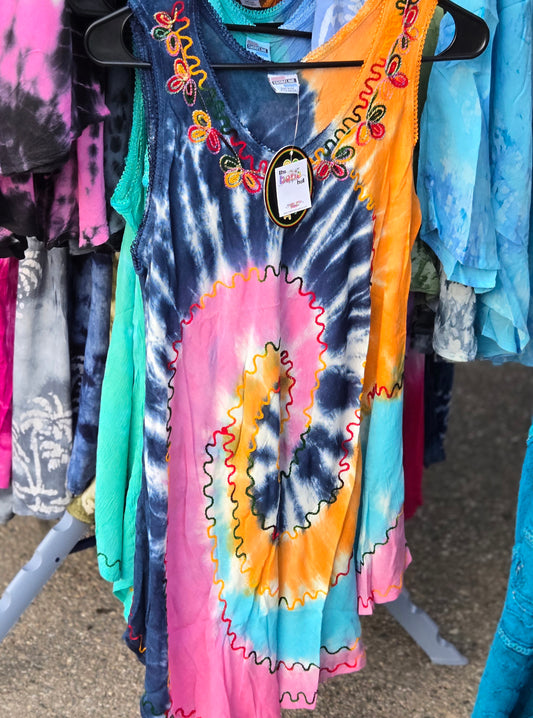 Colorful tie-dye tank top with a spiral pattern on a hanger against a background of other clothing.