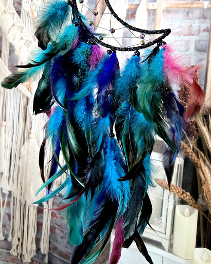 close up of feathers on black and blue crescent moon dream catcher 