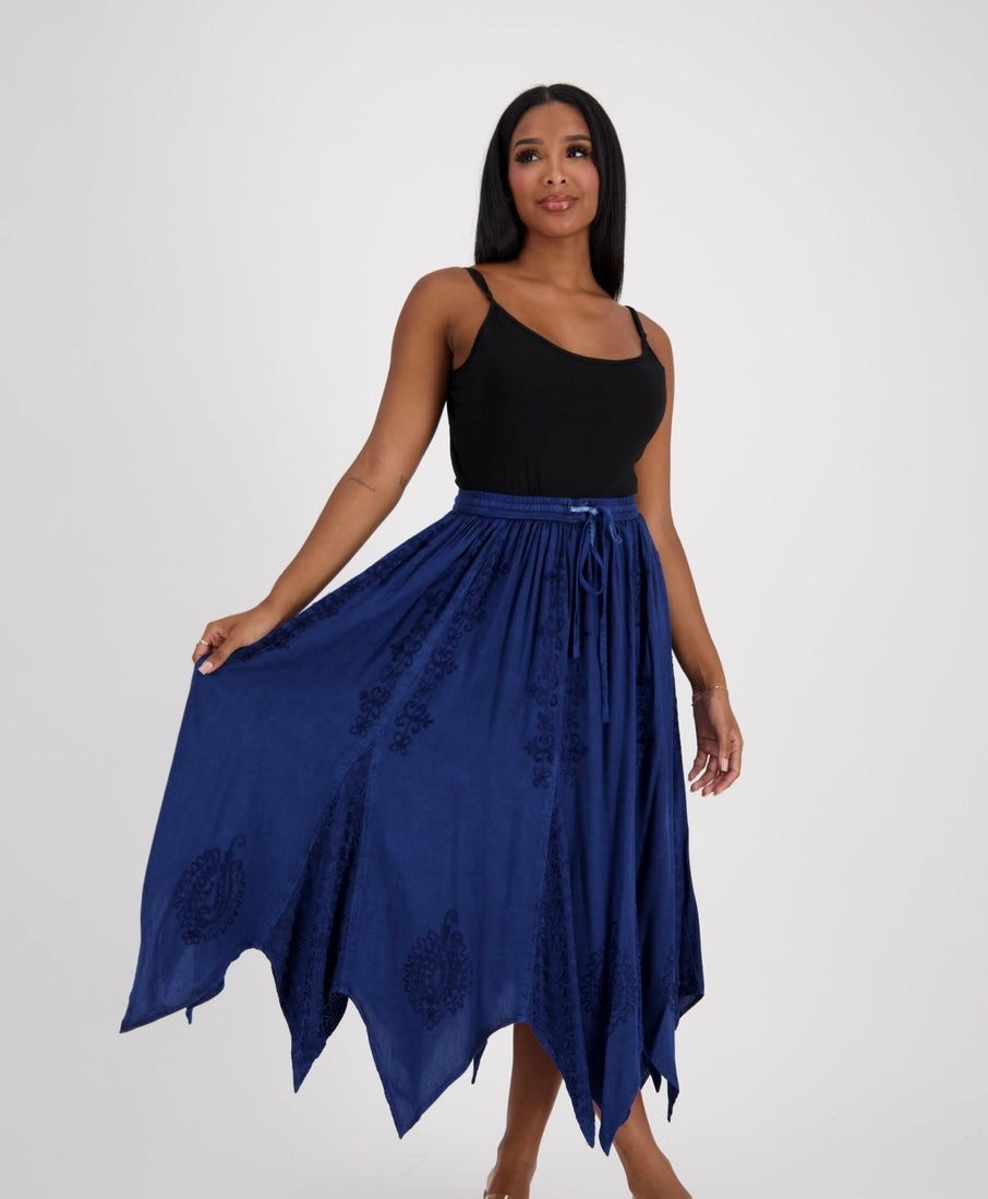 Woman wearing a black top and blue skirt with embroidery on a white background