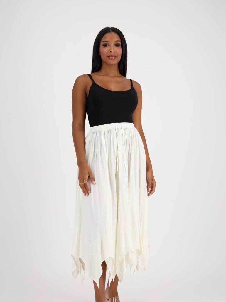 Woman wearing a black top and white flowing skirt on a white background