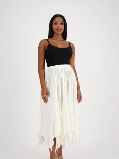 Woman wearing a black top and white flowing skirt on a white background