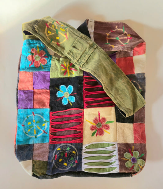 A multicolored hobo bag with a patchwork design, featuring a shoulder strap and a variety of vibrant patterns.