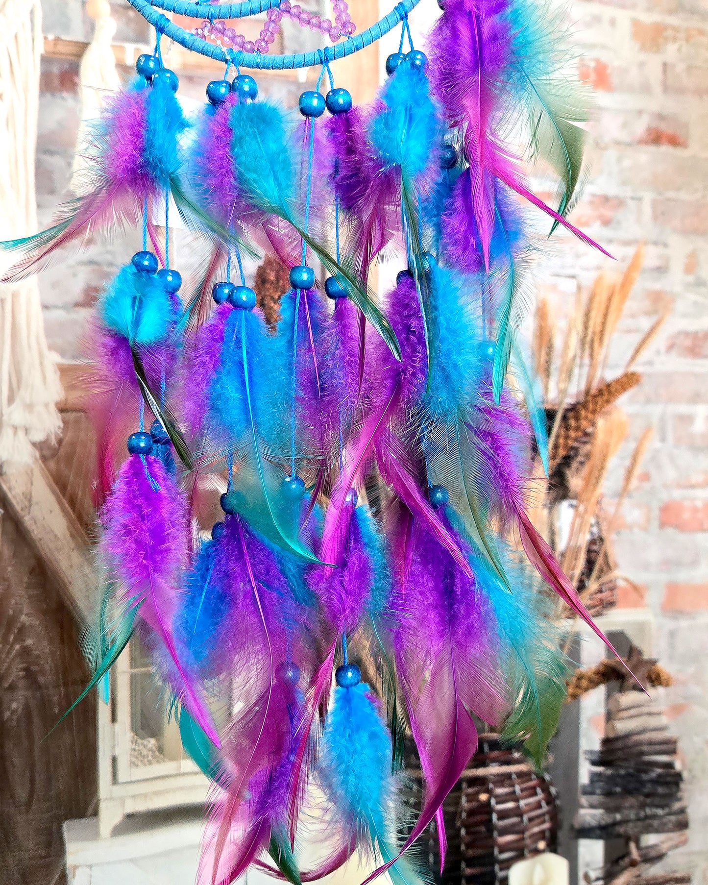 close up of feathers on blue and purple crescent moon dream catcher 