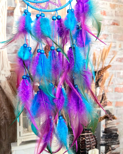 close up of feathers on blue and purple crescent moon dream catcher 