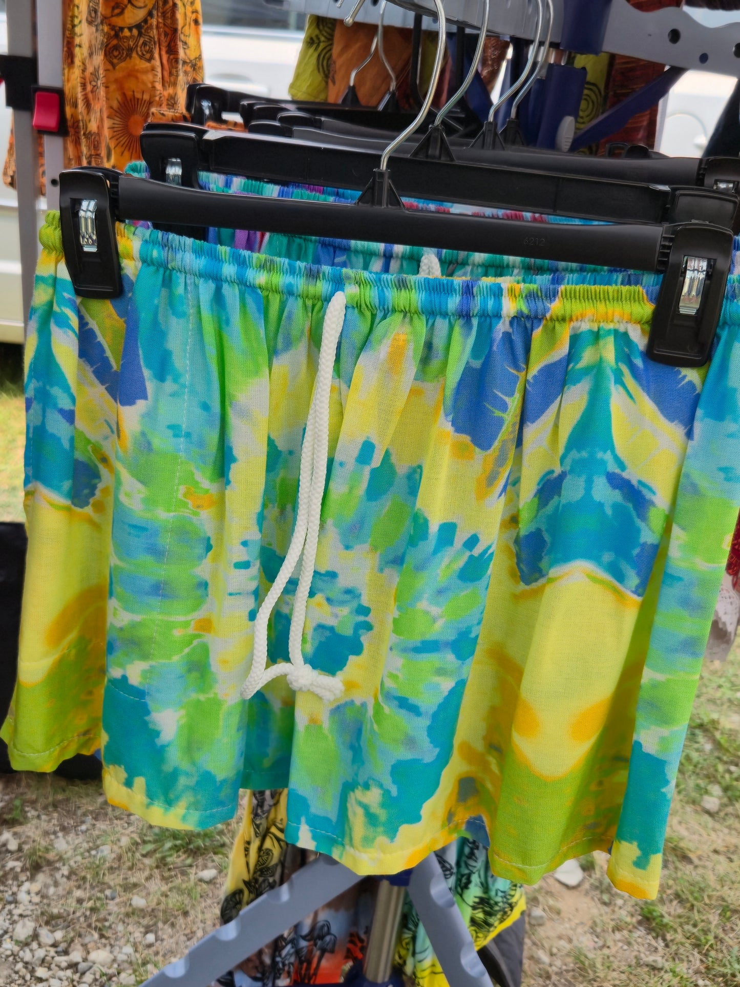 Colorful tie-dye shorts hanging on a rack outdoors.
