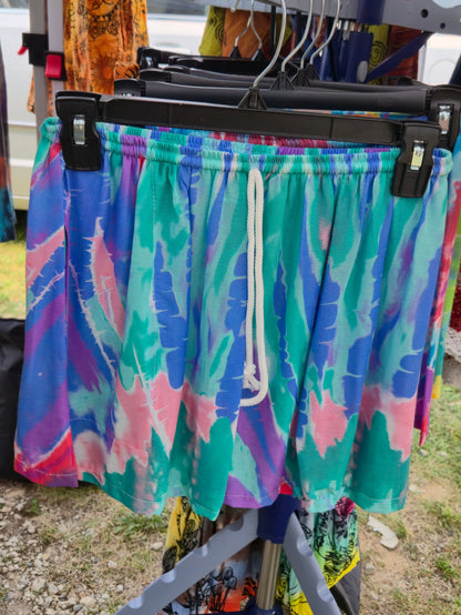 Colorful tie-dye shorts hanging on a rack outdoors.
